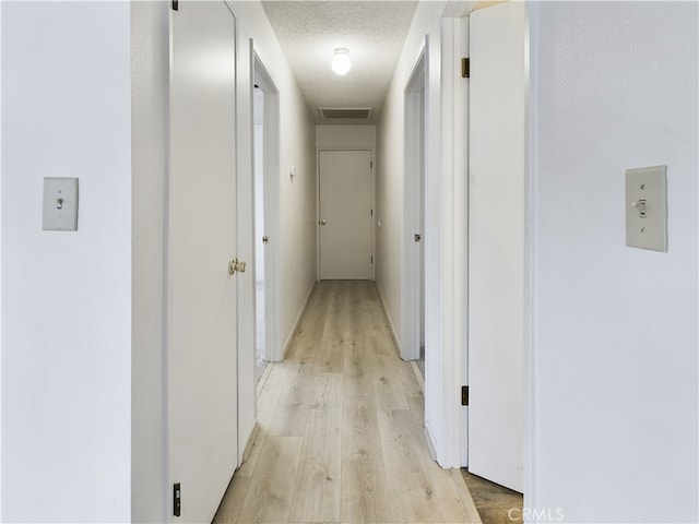 hall featuring a textured ceiling and light wood-type flooring