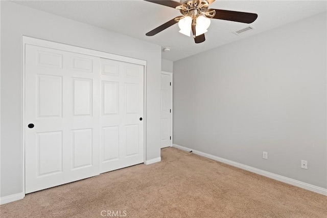 unfurnished bedroom featuring light carpet, ceiling fan, and a closet