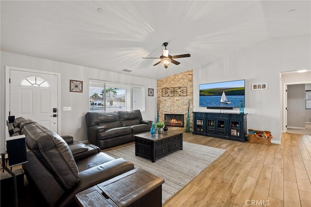 living room featuring a stone fireplace, wood-type flooring, ceiling fan, and vaulted ceiling