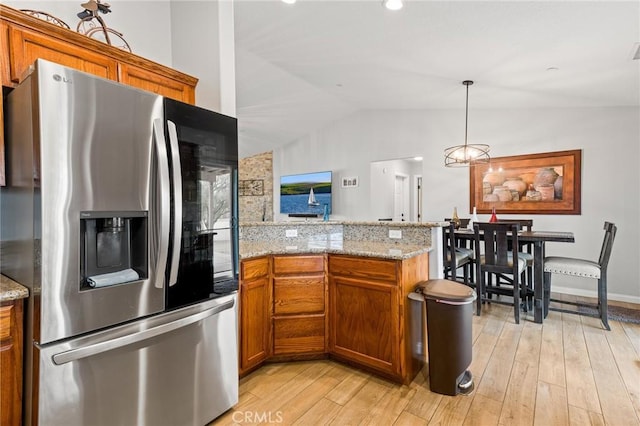 kitchen with hanging light fixtures, stainless steel refrigerator with ice dispenser, light wood-type flooring, and kitchen peninsula