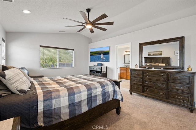 bedroom featuring ceiling fan, light colored carpet, connected bathroom, and vaulted ceiling