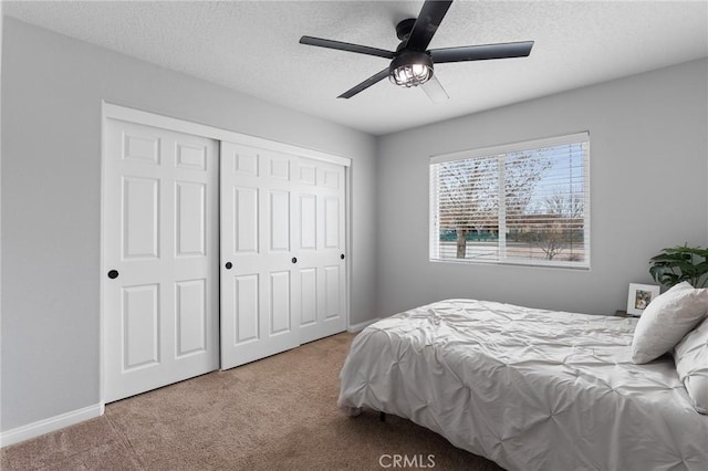 carpeted bedroom with ceiling fan, a textured ceiling, and a closet