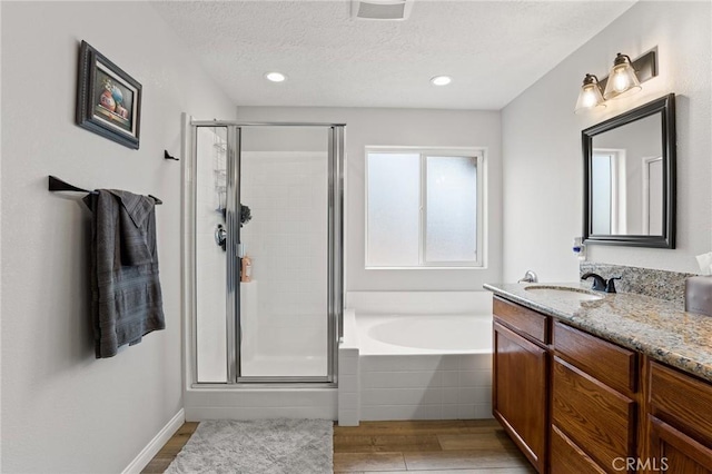 bathroom with shower with separate bathtub, hardwood / wood-style floors, vanity, and a textured ceiling