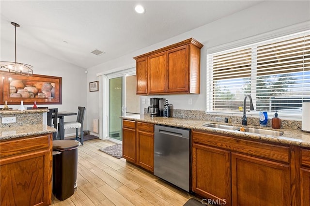 kitchen featuring lofted ceiling, sink, dishwasher, hanging light fixtures, and light stone countertops