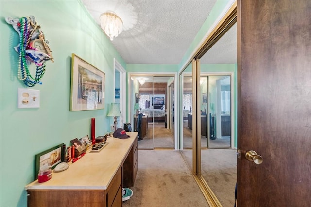 hallway with light colored carpet and a textured ceiling