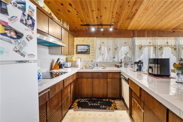 kitchen with sink, tile counters, black electric cooktop, wooden ceiling, and white fridge