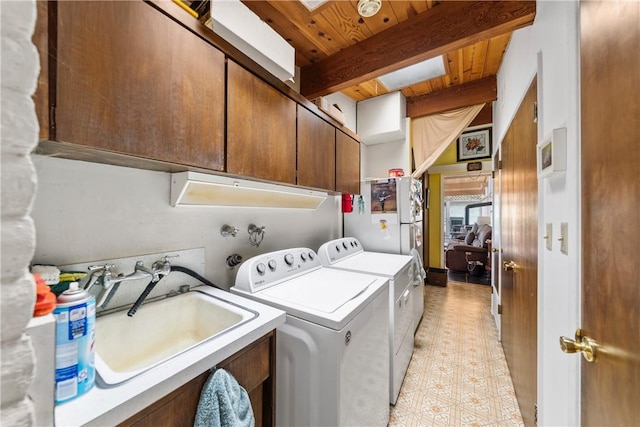 clothes washing area with washer and dryer, sink, wood ceiling, and cabinets