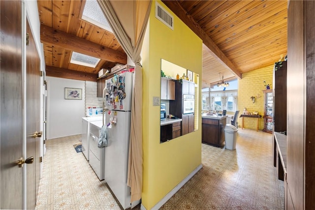 kitchen with lofted ceiling with skylight, stainless steel oven, separate washer and dryer, wooden ceiling, and white fridge