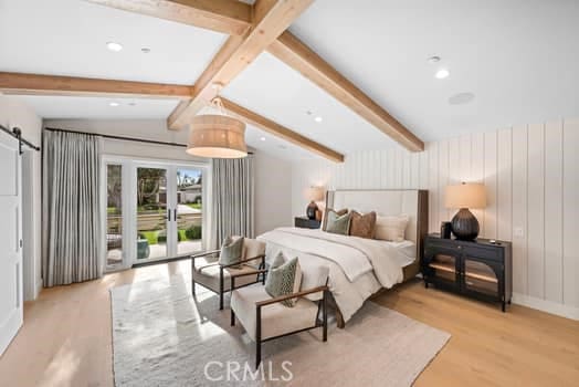 bedroom with a barn door, vaulted ceiling with beams, access to exterior, and light hardwood / wood-style floors