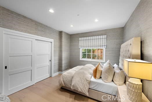 bedroom with light hardwood / wood-style floors and a closet