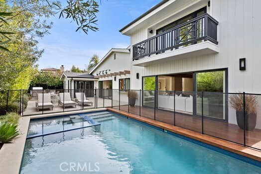 back of property with a balcony and a fenced in pool