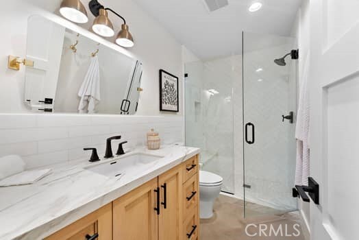 bathroom featuring tasteful backsplash, vanity, toilet, and walk in shower