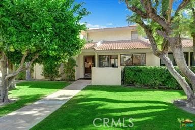 view of front facade featuring a tiled roof, a front lawn, and stucco siding