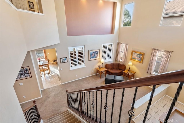 staircase featuring a towering ceiling and carpet floors