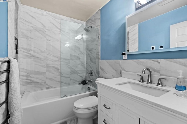 full bathroom featuring tile walls, vanity, tiled shower / bath combo, and toilet