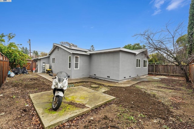 rear view of property featuring a patio area and solar panels