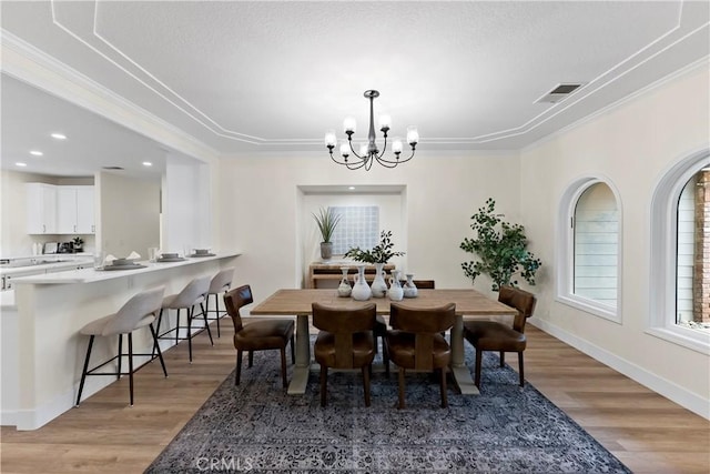 6054 N Woodson Ave, Fresno, CA 93711 - dining room with crown molding, light wood-style flooring, a notable chandelier, and visible vents