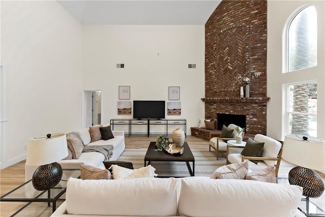 6054 N Woodson Ave, Fresno, CA 93711 - living area featuring light wood finished floors, visible vents, a brick fireplace, and a high ceiling