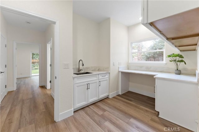 6054 N Woodson Ave, Fresno, CA 93711 - kitchen with a wealth of natural light, light wood-style flooring, white cabinetry, and a sink