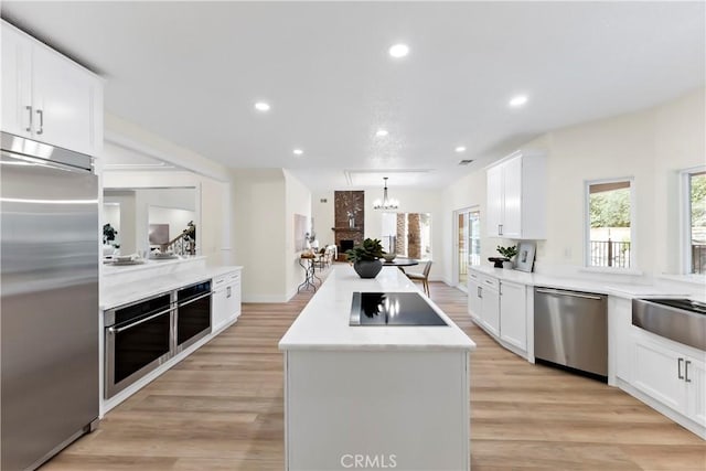6054 N Woodson Ave, Fresno, CA 93711 - kitchen with light countertops, appliances with stainless steel finishes, white cabinetry, light wood-type flooring, and a center island