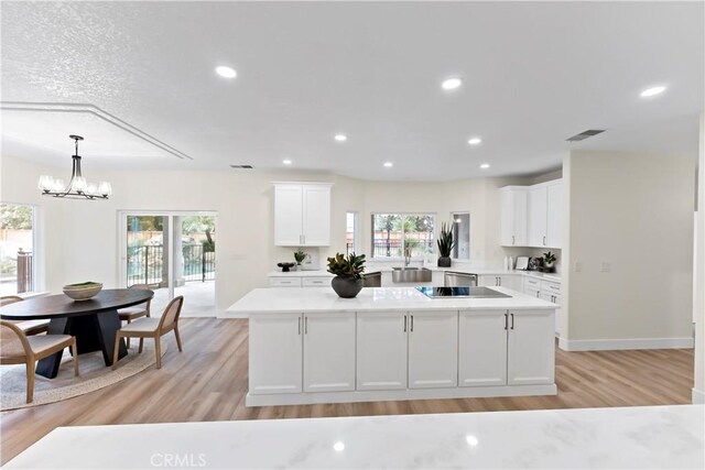 6054 N Woodson Ave, Fresno, CA 93711 - kitchen with light wood-style flooring, white cabinets, a center island, and light countertops