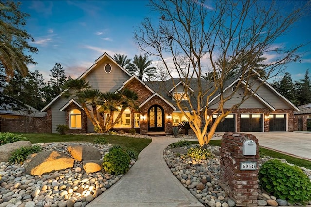 view of front of home with brick siding, french doors, and concrete driveway