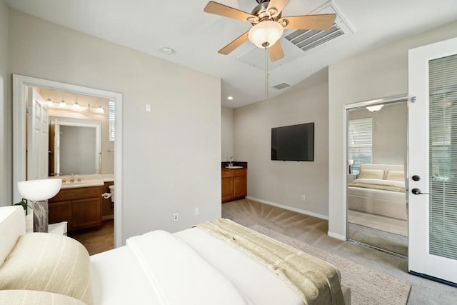 carpeted bedroom featuring sink, ensuite bath, and ceiling fan