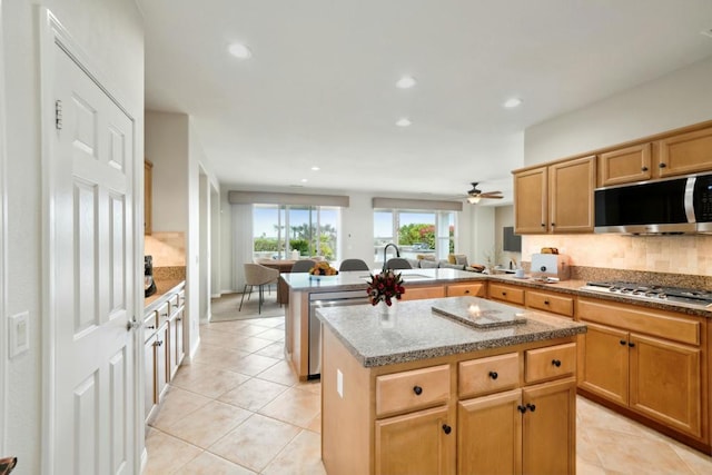 kitchen featuring a kitchen island, stainless steel appliances, light stone counters, light tile patterned flooring, and kitchen peninsula