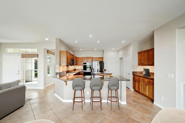 kitchen with appliances with stainless steel finishes, a breakfast bar, light tile patterned floors, and sink