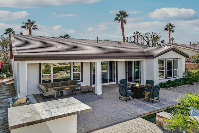 rear view of property with a patio and an outdoor living space with a fire pit