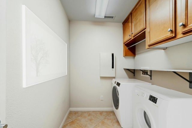 laundry room featuring cabinets, light tile patterned floors, and washing machine and clothes dryer