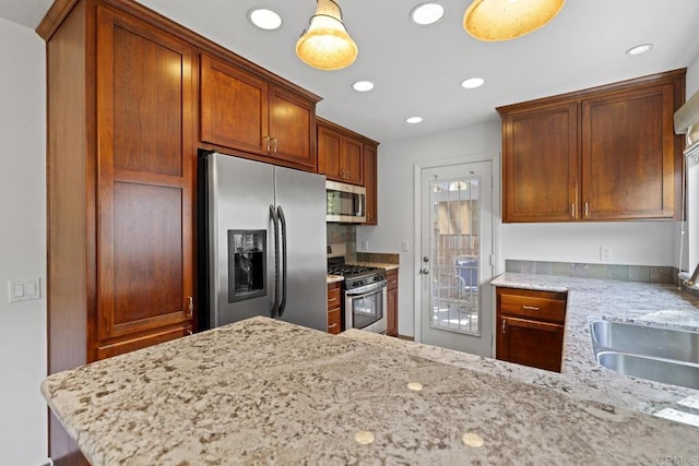 kitchen with pendant lighting, light stone countertops, stainless steel appliances, and kitchen peninsula