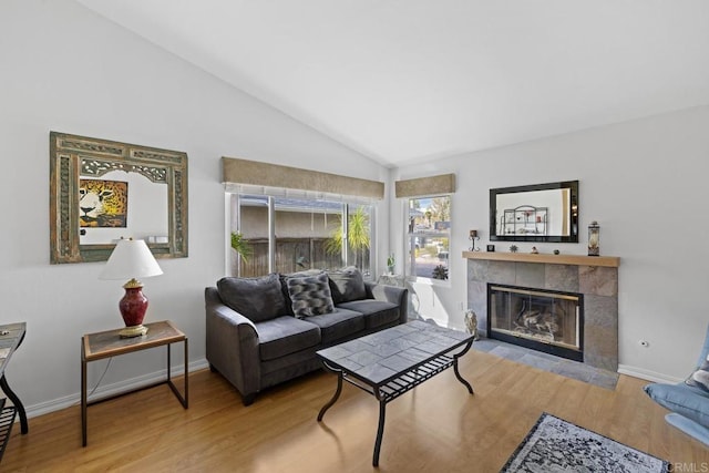 living room with lofted ceiling, a tiled fireplace, and light hardwood / wood-style flooring