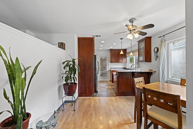 kitchen featuring pendant lighting, sink, ceiling fan, kitchen peninsula, and light wood-type flooring