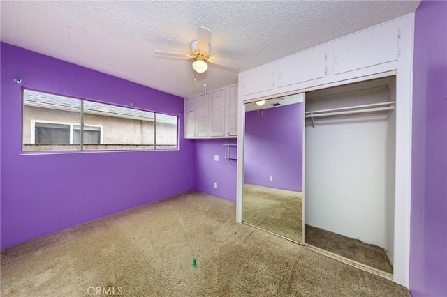 unfurnished bedroom featuring ceiling fan, a closet, light carpet, and a textured ceiling