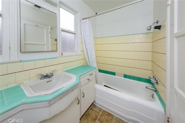 bathroom with shower / tub combo, vanity, tasteful backsplash, and tile walls