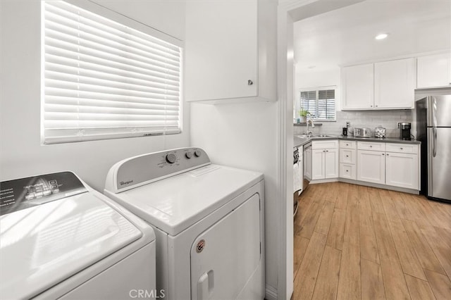 laundry area featuring sink, light hardwood / wood-style floors, and independent washer and dryer