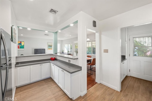 kitchen with stainless steel refrigerator, light hardwood / wood-style flooring, and white cabinets