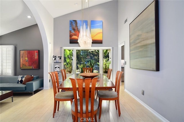 dining space with light wood-type flooring and high vaulted ceiling