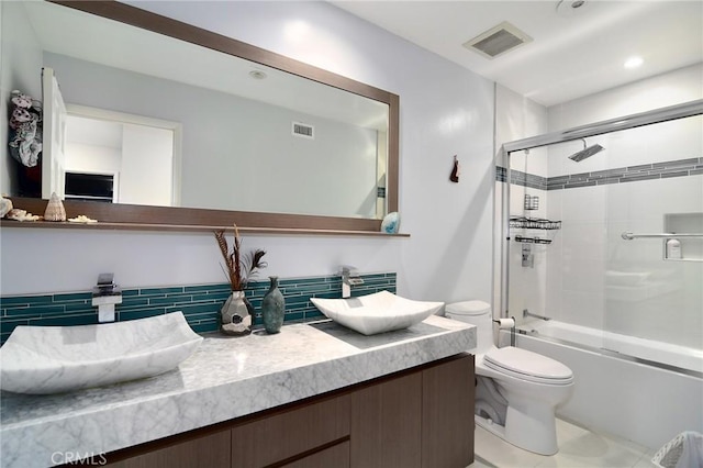 full bathroom featuring tasteful backsplash, vanity, shower / bath combination with glass door, and toilet