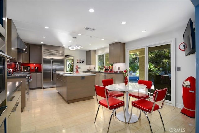 kitchen with a kitchen island, pendant lighting, sink, dark brown cabinetry, and stainless steel appliances