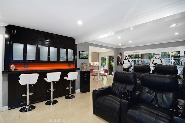 cinema room with beamed ceiling, ornamental molding, bar, and light hardwood / wood-style flooring