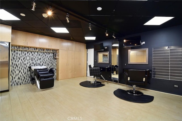 workout room with a paneled ceiling, light hardwood / wood-style flooring, and elevator