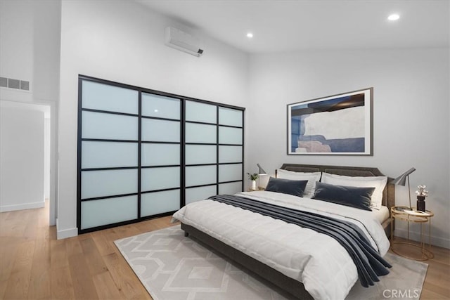 bedroom featuring light hardwood / wood-style flooring and an AC wall unit