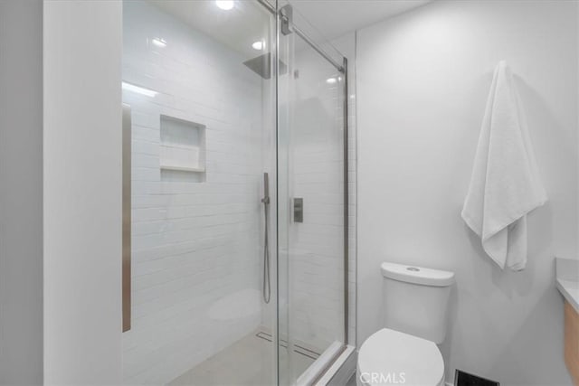 bathroom featuring an enclosed shower, vanity, and toilet