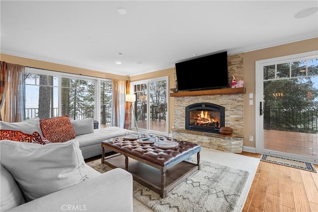 living room featuring crown molding, a stone fireplace, and hardwood / wood-style flooring