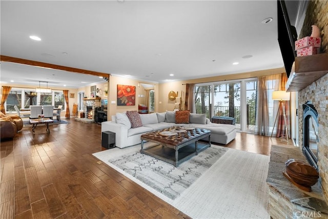 living room with ornamental molding, wood-type flooring, and a stone fireplace