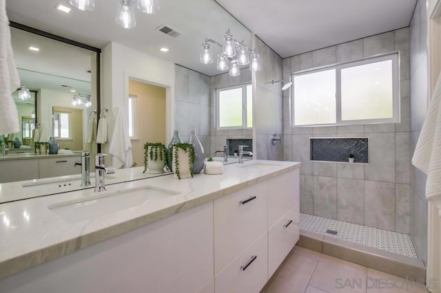 bathroom with a tile shower, vanity, tile patterned flooring, and tile walls