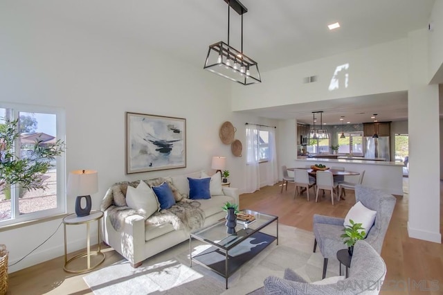 living room with an inviting chandelier, light hardwood / wood-style flooring, and a high ceiling