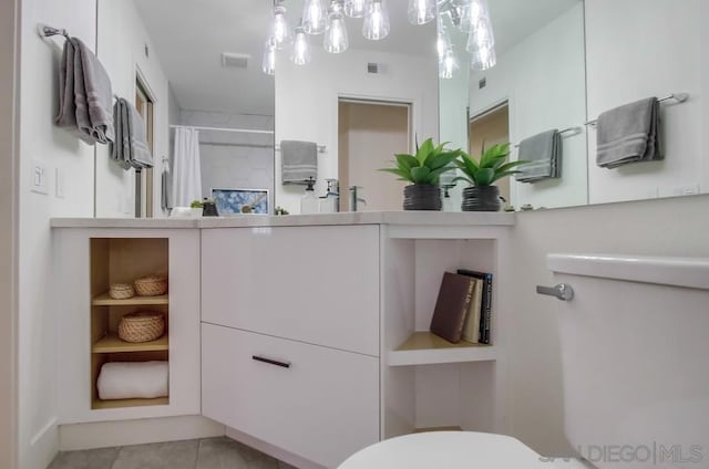 bathroom featuring walk in shower, vanity, toilet, and tile patterned flooring